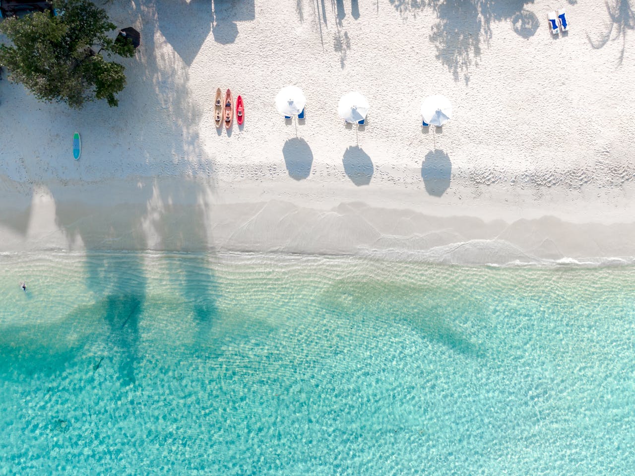hero-img-01 Stunning aerial view of a tropical beach with white sand and turquoise waters, perfect for a seaside escape.