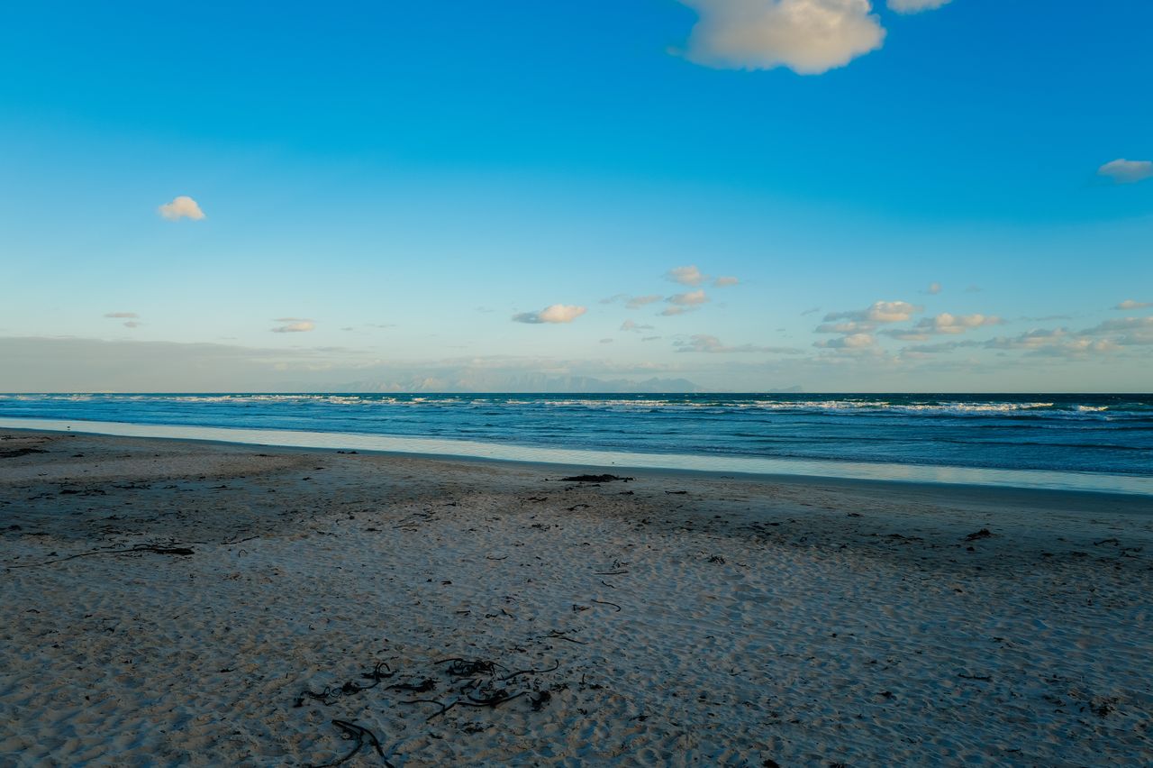 Peaceful beach with gentle ocean waves under a bright blue sky, perfect for relaxation.